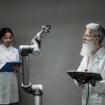 Dois cientistas trabalham com um braço robótico em um laboratório de pesquisa.
