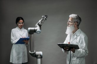 Dois cientistas trabalham com um braço robótico em um laboratório de pesquisa.