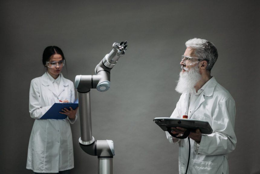 Dois cientistas trabalham com um braço robótico em um laboratório de pesquisa.