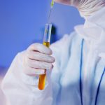 Cientista usando equipamento de proteção manipula um tubo de ensaio em um laboratório.