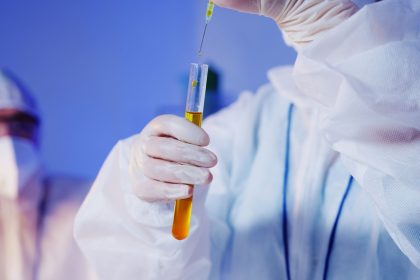 Cientista usando equipamento de proteção manipula um tubo de ensaio em um laboratório.