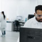 Cientista trabalha em um computador dentro de um laboratório moderno.