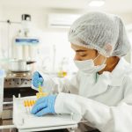 Cientista usando equipamento de proteção realiza experimento em um laboratório.