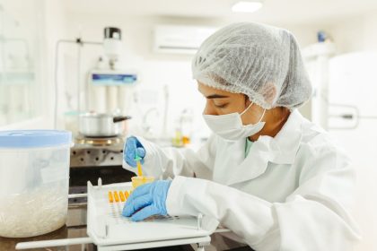 Cientista usando equipamento de proteção realiza experimento em um laboratório.