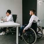 Equipe diversa reunida em um escritório, participando de uma discussão sobre inclusão e acessibilidade no trabalho.